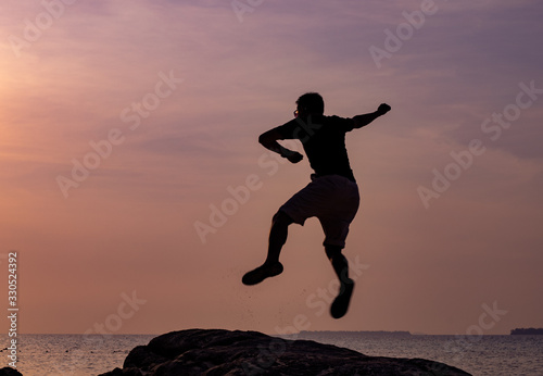  silhouette of a boy jumping at sunset over the sea