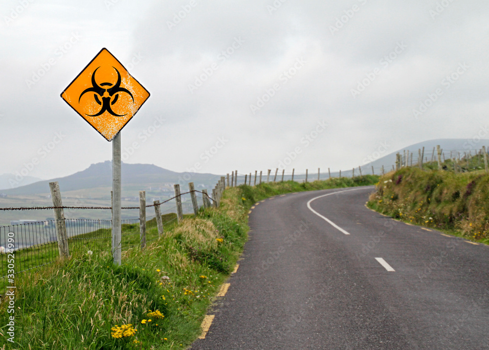 Road sign with bio hazard symbol in front of a curve