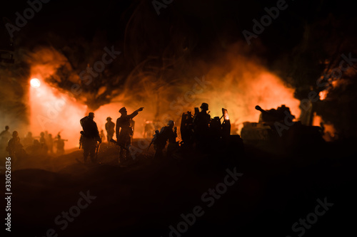 War Concept. Armored vehicle silhouette fighting scene on war foggy sky background at night.