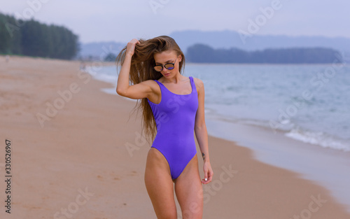 Beautiful slim girl in a blue swimsuit on the ocean.