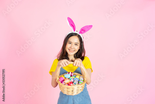 Asian woman wear bunny ear hold easter eggs basket