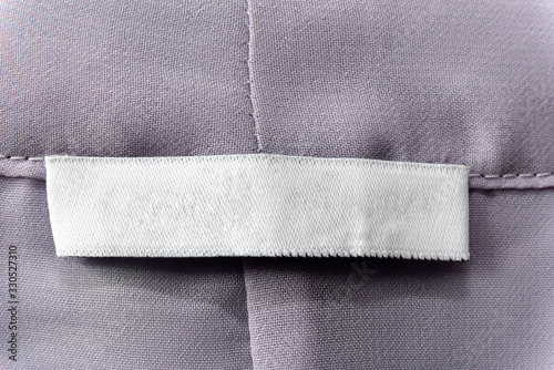 white blank clothes label on worn pink gray shirt background