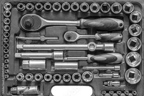 Black and white men tools background. Worker tools and equipment close-up. A set of wrenches and screwdrivers are laid out in the cells of the box.