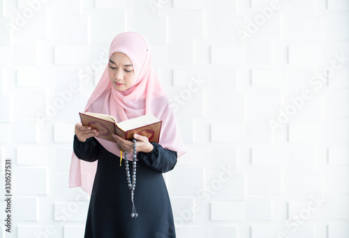 Beautiful young asian muslim woman reading quran photo