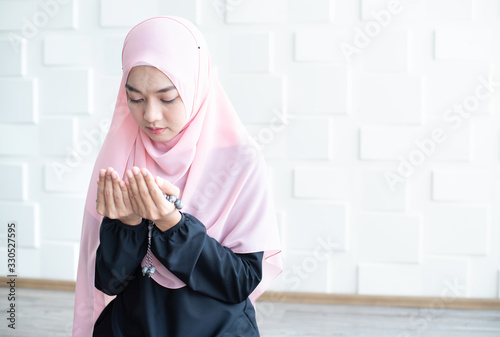 Muslim woman praying near light wall photo