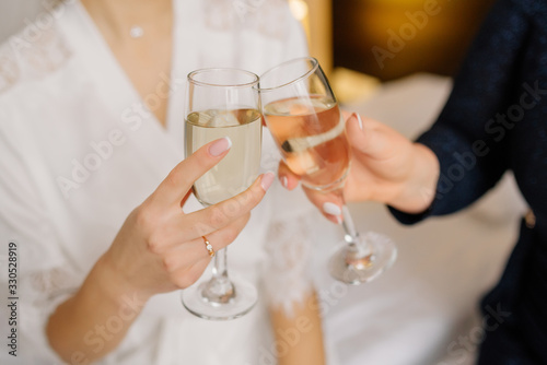 Gorgeous bride and bridesmaid toasting champagne and having fun on wedding morning. Cheerful young girlfriends raise a toast and clink glasses. Bride morning. Wedding day © deineka