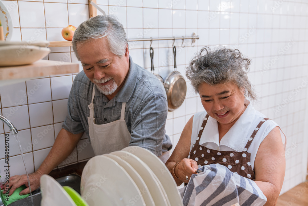 Happy couple Asian elder washing dishes in the sink together in the kitchen at home Happy couple Asian elder washing dishes in the sink together in the kitchen at home
