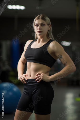 Portrait of a blond-haired girl with in the gym standing in a sports position.