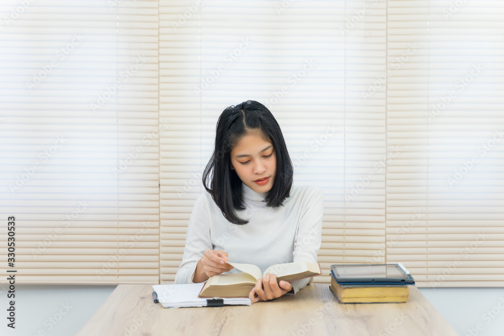 Young cheerful Asian student female university student studying in self study room in the university library to do her assignment and prepare for examination. Young cheerful Asian student female university student studying in self study room in the university library to do her assignment and prepare for examination.