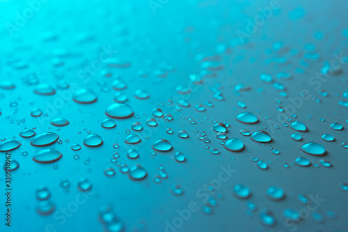 Many different drops of water rain on a blue background, close up