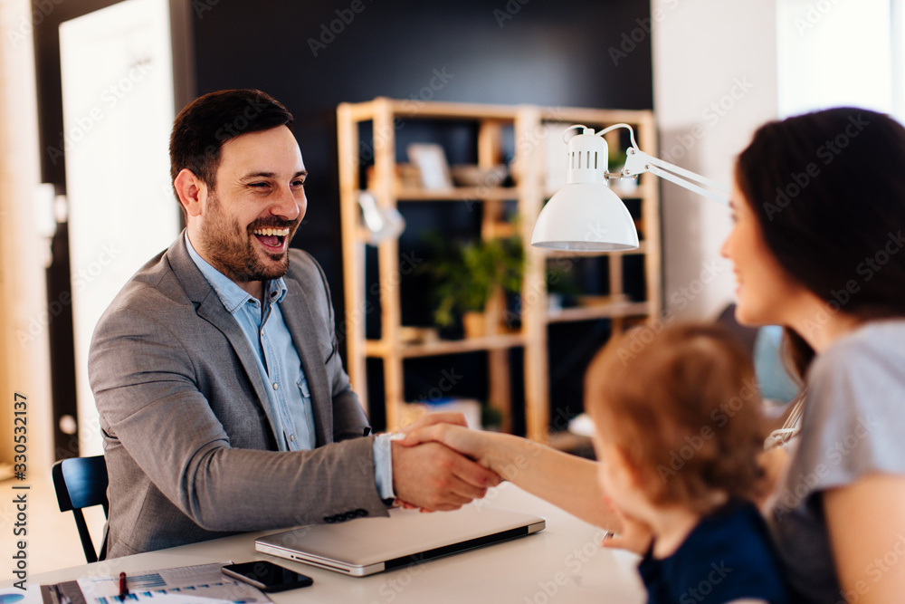 Single mother with a small child in her lap shakes hands with manager in the bank Single mother with a small child in her lap shakes hands with manager in the bank