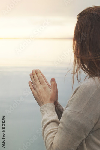 woman in meditation prays in front of the ocean