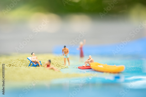 Fototapeta Naklejka Na Ścianę i Meble -  Miniature people, travelers relaxing on the sand box decorating in summer theme using as background travel, exploring the world, budget trip concept.