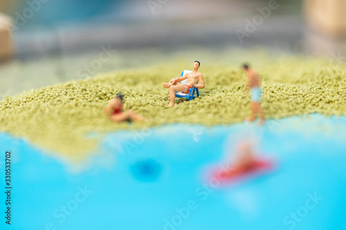 Miniature people, travelers relaxing on the sand box decorating in summer theme using as background travel, exploring the world, budget trip concept.