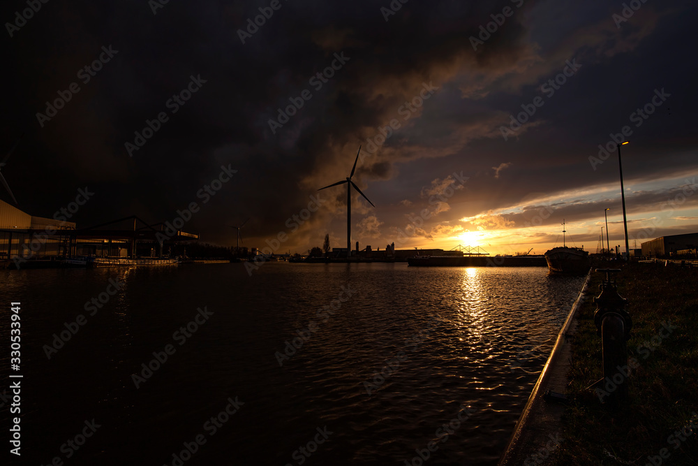 Boats on water at sunset and one windmill