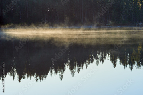 Mist over Blue lake surface at sunrise. Indian Heaven wilderness in Washington state in the USA.