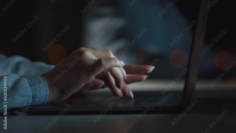 Female hands is typing on a laptop at night Female hands is typing on a laptop at night
