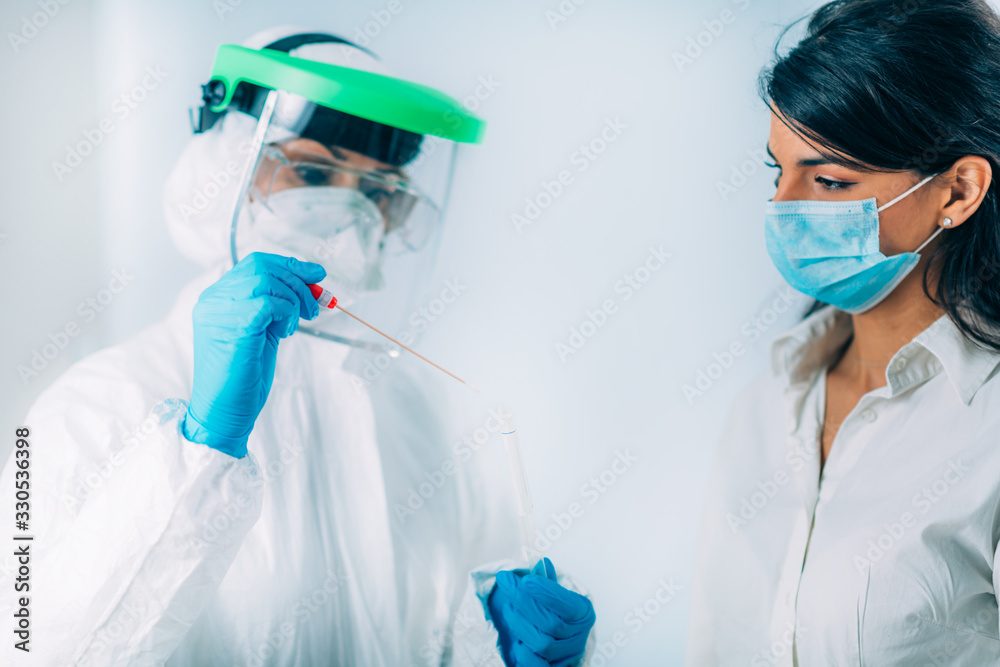 Coronavirus test. Medical worker in protective suite taking a swab for corona virus test, potentially infected young woman - obrazy, fototapety, plakaty 