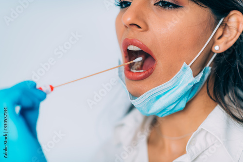 Coronavirus test. Medical worker in protective suite taking a swab for corona virus test  potentially infected young woman