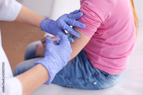 Foto Little girl receiving chickenpox vaccination in clinic, closeup
