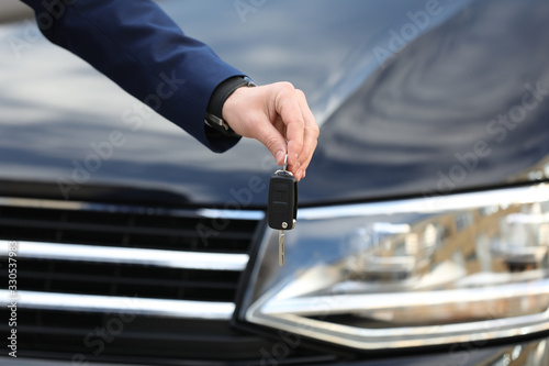 Man holding key in modern auto dealership  closeup. Buying new car