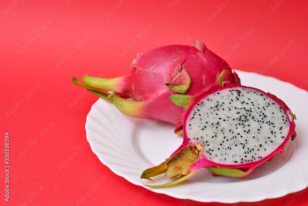 Close up view of exotic dragon fruit cut and whole sliced isolated on a blue background with leafs and petals. Close up view of exotic dragon fruit cut and whole sliced isolated on a blue background with leafs and petals.