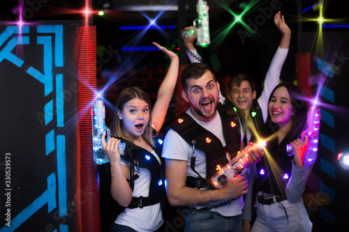 Young people in colorful beams on lasertag arena