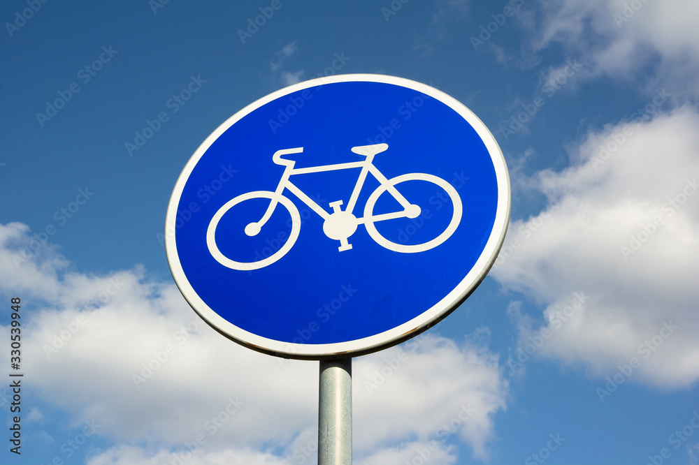 Traffic sign and roadsign is marking track for cycling - Cycle road and bike path. Blue sky with clouds in the background. Traffic sign and roadsign is marking track for cycling - Cycle road and bike path. Blue sky with clouds in the background.
