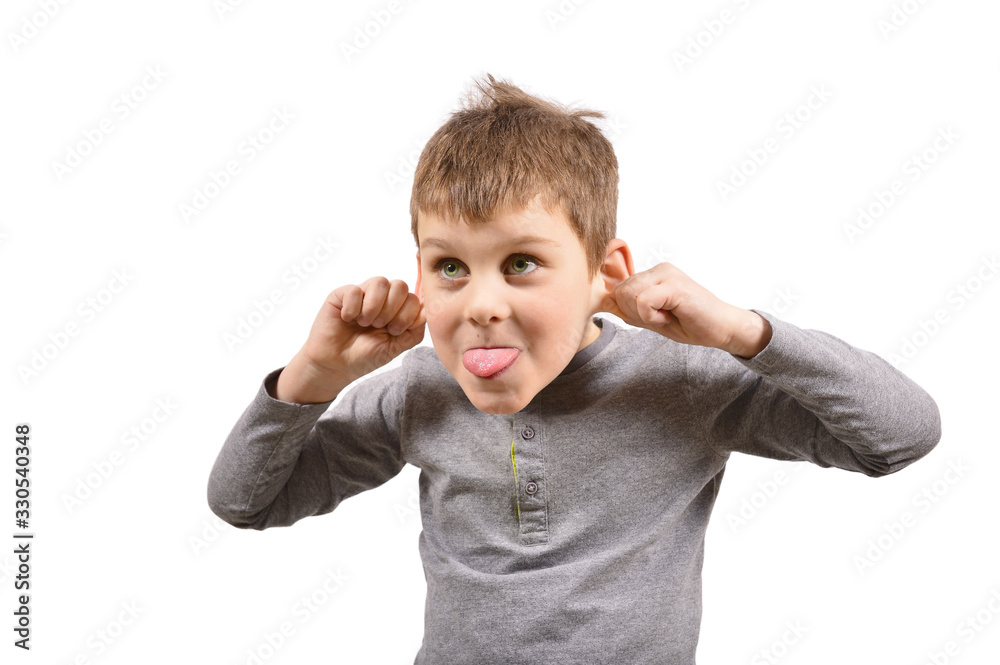 a small cheerful boy shows his tongue and pulls back his ears. A child makes a face on a white background a small cheerful boy shows his tongue and pulls back his ears. A child makes a face on a white background
