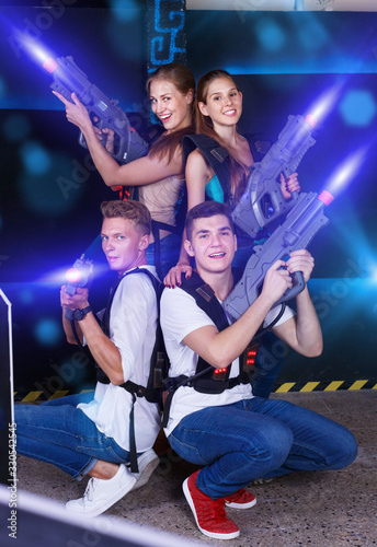 Group portrait of joyful young people with laser guns in their h