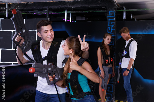 Triumphing team of laser tag winners guy and girl in foreground and losers team