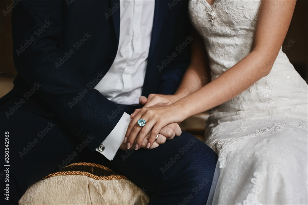 Close up cropped photo of male and female hands with expensive wedding rings. Male hands holding beautiful female hands with cute manicure and expensive gold ring with big diamond