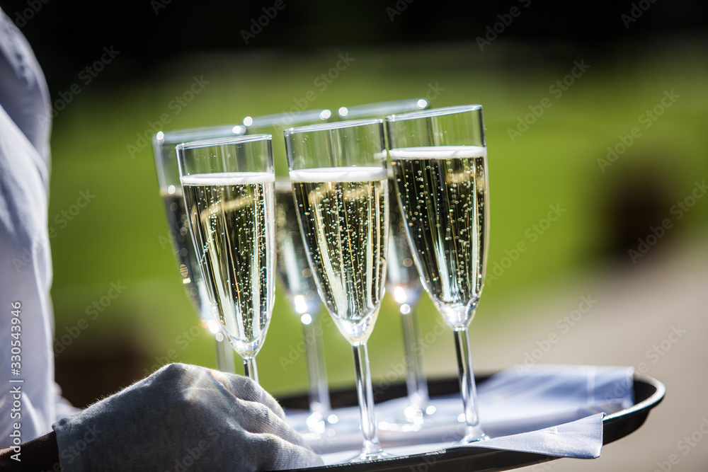 a waiter carries glasses of champagne
