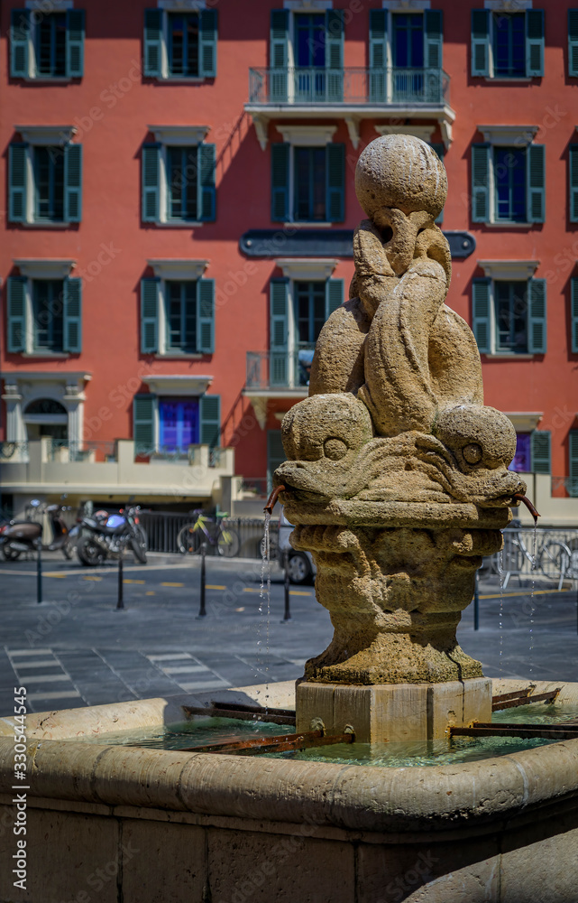 A dolphin fountain with old traditional houses in the background in Old Town Vielle Ville in Nice in the South of France