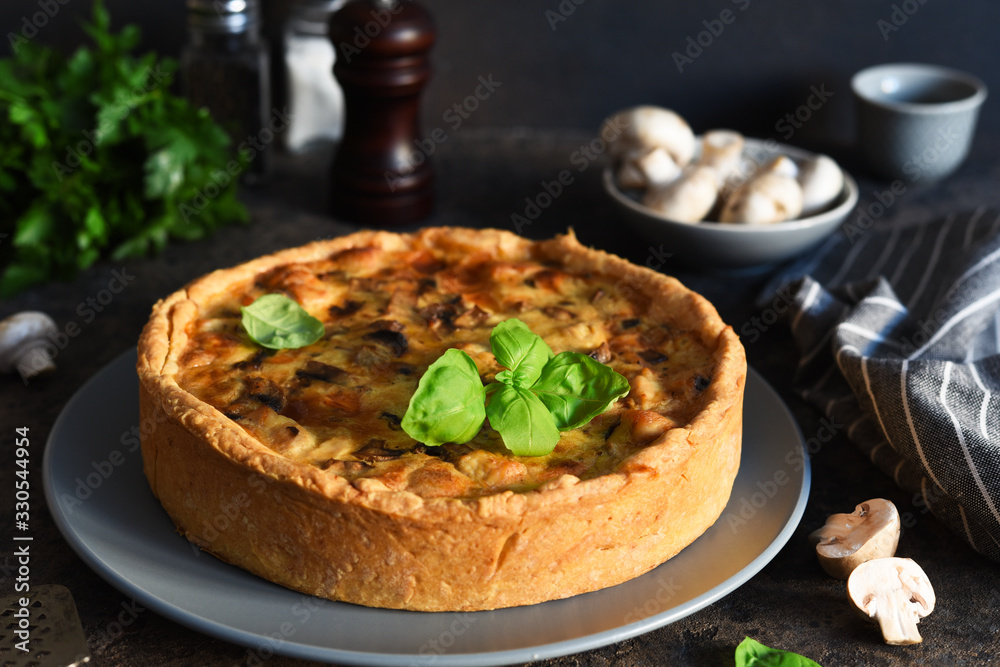 Quiche with chicken, mushrooms and cheese on a dark concrete background. Just on the kitchen table. Quiche with chicken, mushrooms and cheese on a dark concrete background. Just on the kitchen table.