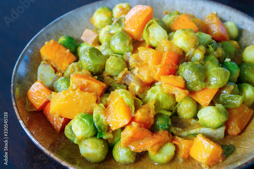 Dish with a delicious meal of mixed vegatables and tofu. Curry of Brussels sprouts, pumpkin and onion. Dark background.