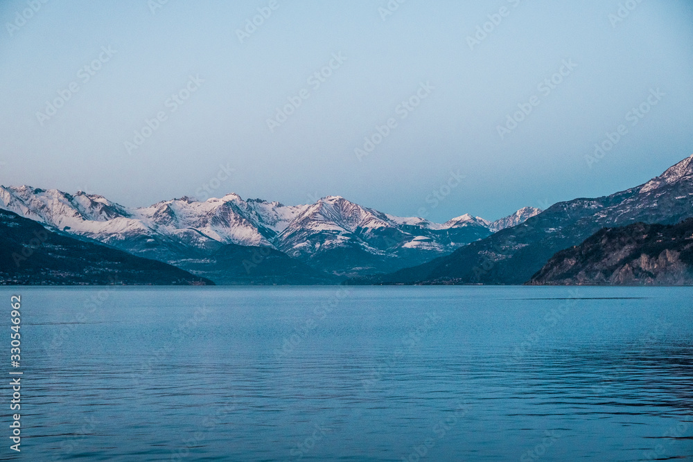 Snowy peaks of Alps mountains on a clear sunset sky. Panorama of Lago Di Como 