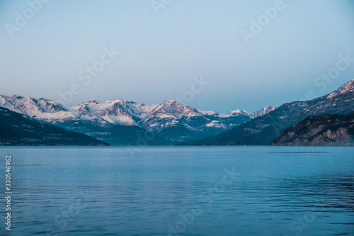 Snowy peaks of Alps mountains on a clear sunset sky. Panorama of Lago Di Como 
