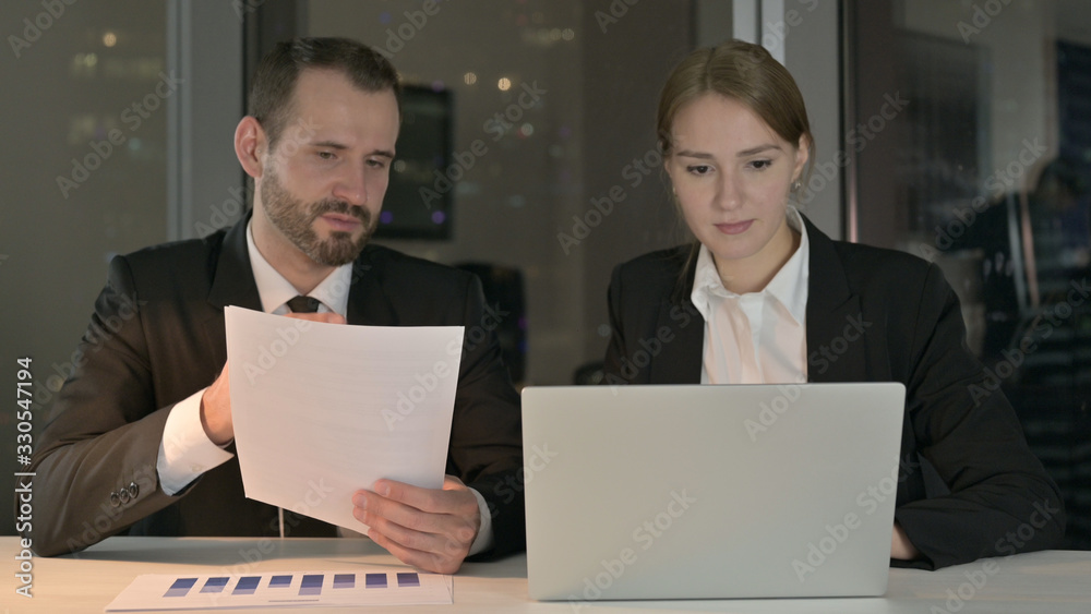 The Business people Working on Documents and Laptop at Night The Business people Working on Documents and Laptop at Night