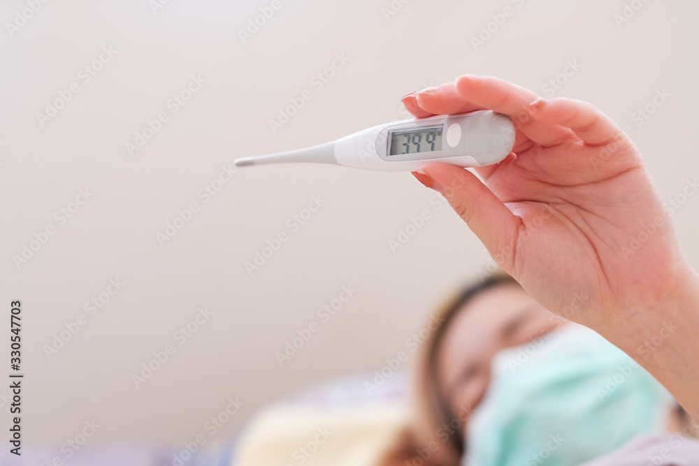 Ill woman looking at thermometer. Ill woman looking at thermometer.