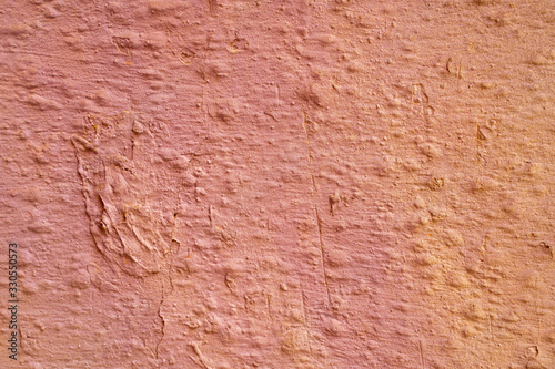 Salmon color gradient paint on a stucco scratched wall. Close-up of a graffiti texture. Street art background.