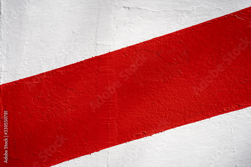 Diagonal red stripe on a white wall. Background texture.