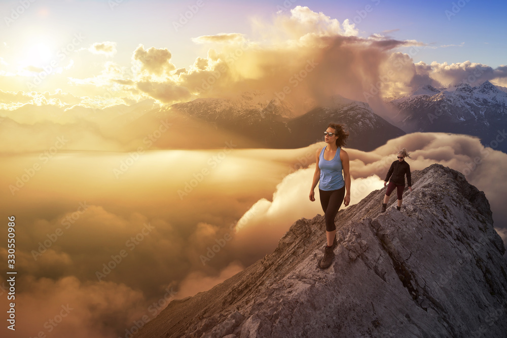 Girl Hiking on a mountain with Beautiful and striking view of the puffy clouds during a colorful and vibrant sunset or sunrise. Nature Background. Concept: Freedom, Lifestyle, Adventure, Hike, Explore