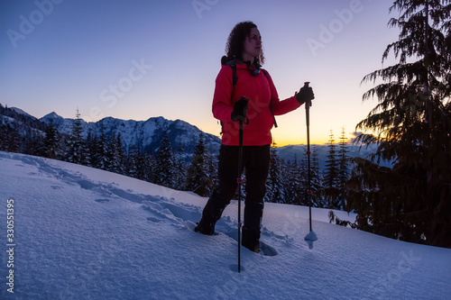 Adventurous Girl Snowshoeing in the snow on top of a mountain during a vibrant and colorful winter sunset. Taken on Anif Peak, Squamish, British Columbia, Canada. Concept: explore, adventure photo