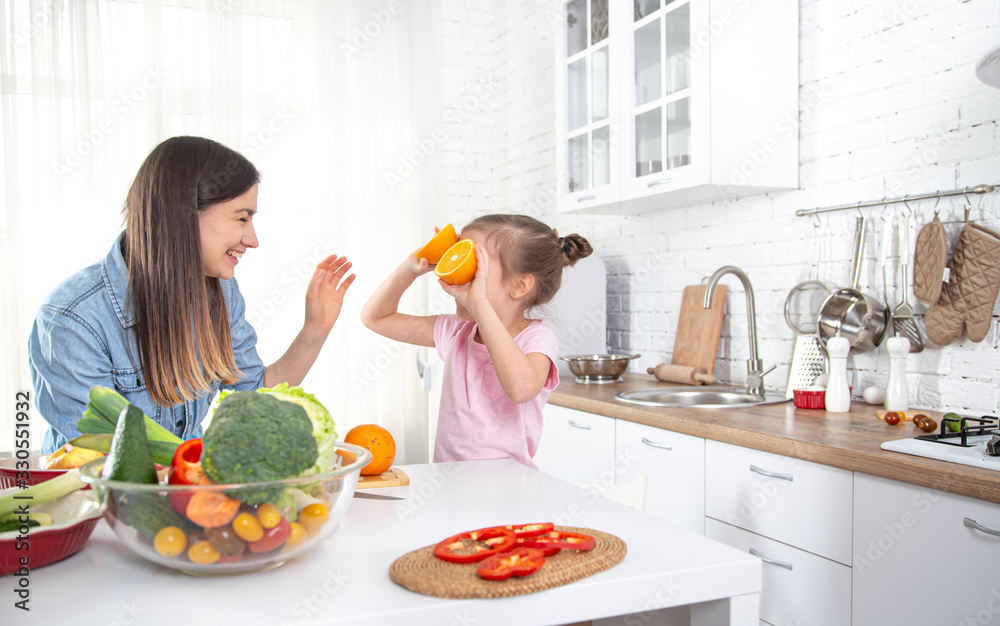 Mom and daughter in the kitchen with fruits and vegetables. Mom and daughter in the kitchen with fruits and vegetables.
