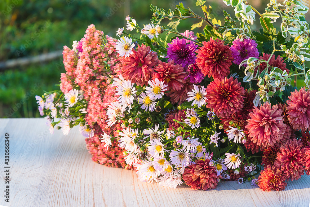 Bunch of summer and autumn flowers on table on sunlight