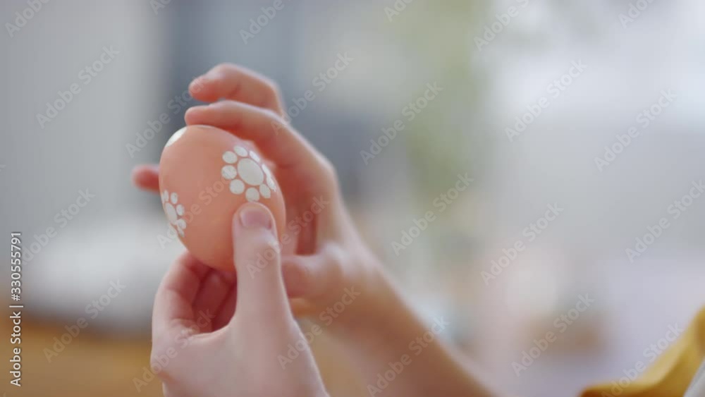 Handheld tilt down shot with close up of cute girl looking at dyed Easter egg with hand-painted pattern Handheld tilt down shot with close up of cute girl looking at dyed Easter egg with hand-painted pattern