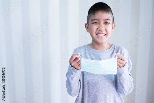 Portrait Asian kid wearing medical mask.A boy wearing mouth mask against air smog pollution. Concept of corona virus quarantine or covid-19.Protection against virus and infection control concept. © arcyto