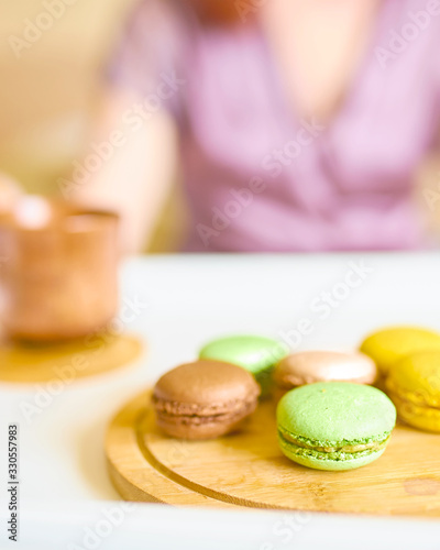 Young beautiful caucasian woman is enjoying her morning breakfast of black coffee, French macarons served on a tray. Breakfast in bed concept