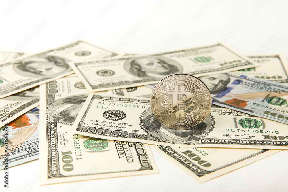 bitcoin coin on the background of one hundred dollars bills.